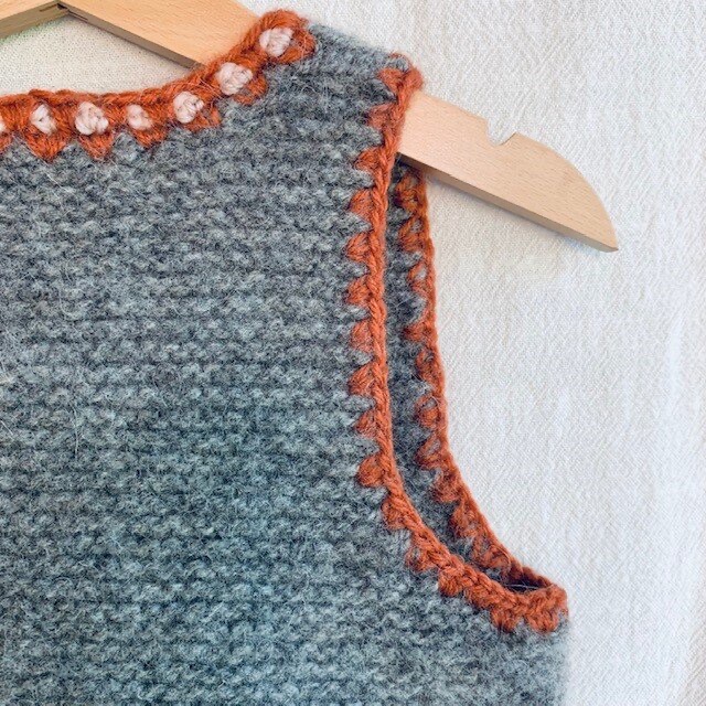 Screenshot von wunderlang.com (Wunderlang, 2018), abgerufen am 07.06.2025. Kraus rechts gestrickte Kinderweste mit einer farblich abgesetzten Häkelkante. https://www.wunderlang.com/shop-1/wanderer-vest-bdt3k-y68r4-mj7y4